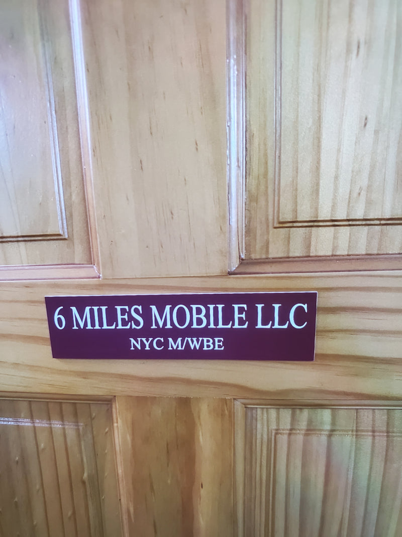 Wooden door with a purple sign reading '6 Miles Mobile LLC' on a wooden wall.