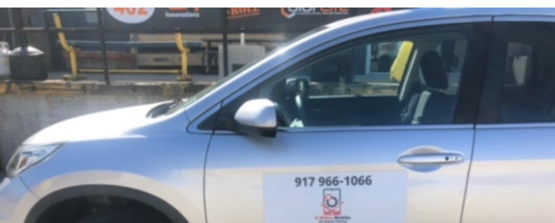 Car with a phone number on the side, parked outdoors.