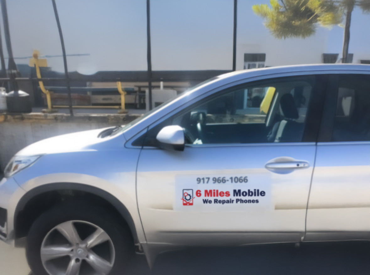 White car with '6 Miles Mobile' advertisement on a road.