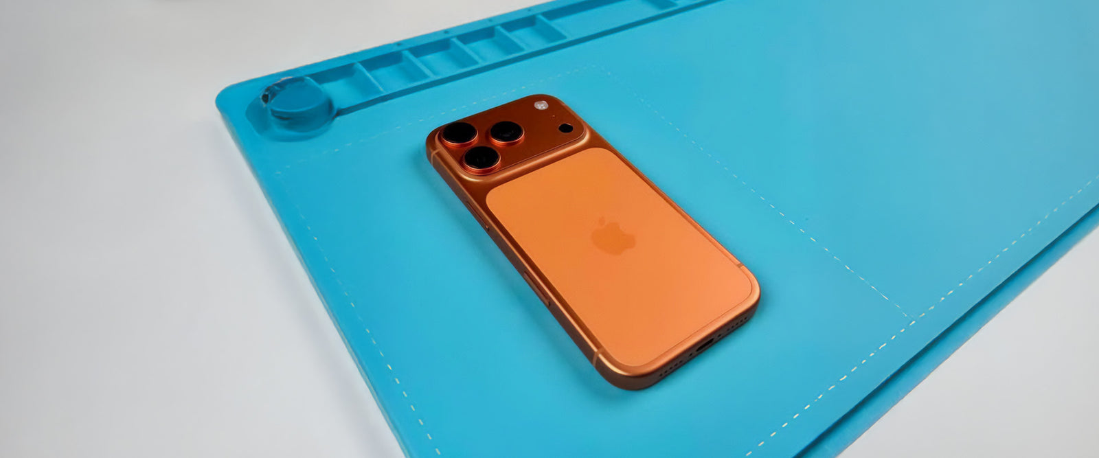 Orange phone on a blue cutting mat with a white background