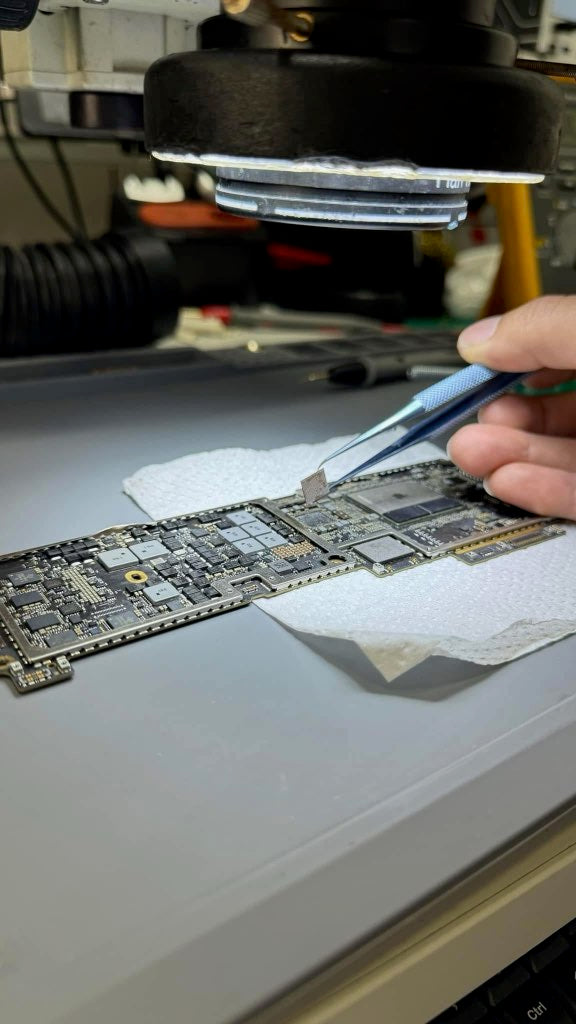 Person working on a circuit board with tweezers in a workshop setting