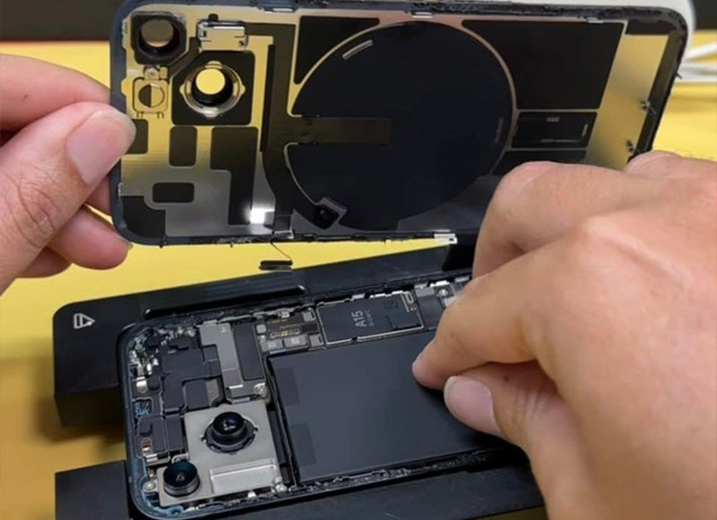 Person repairing a disassembled electronic device on a yellow surface