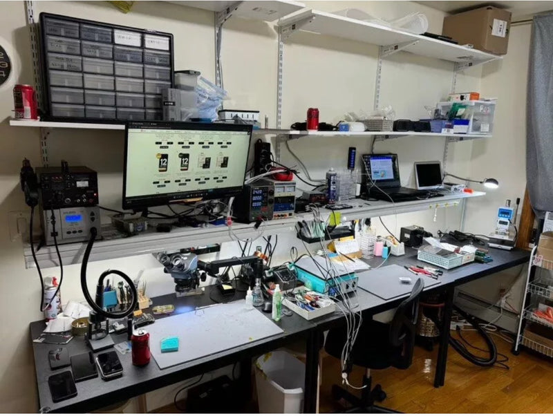 Technical workspace with computer monitors, equipment, and tools on a desk.