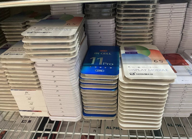 Stacks of phone screen replacement parts on a metal shelf