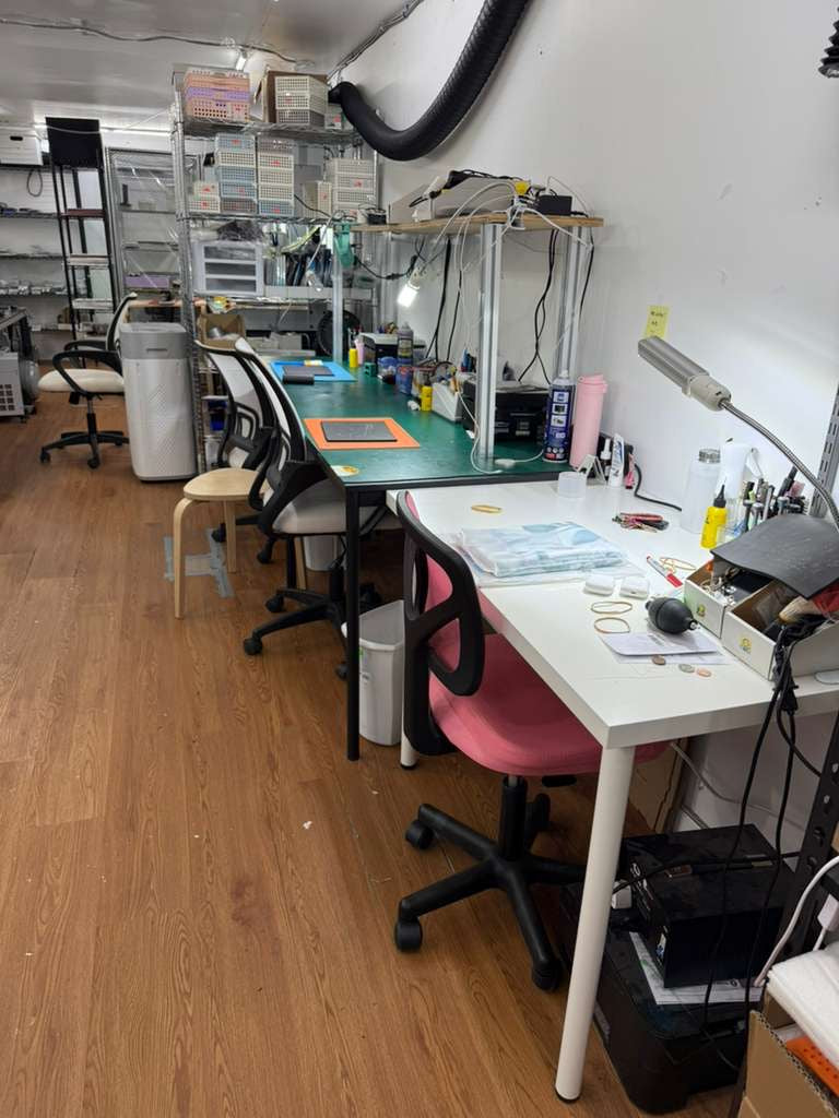Workshop or office space with desks, chairs, and various items on a wooden floor.